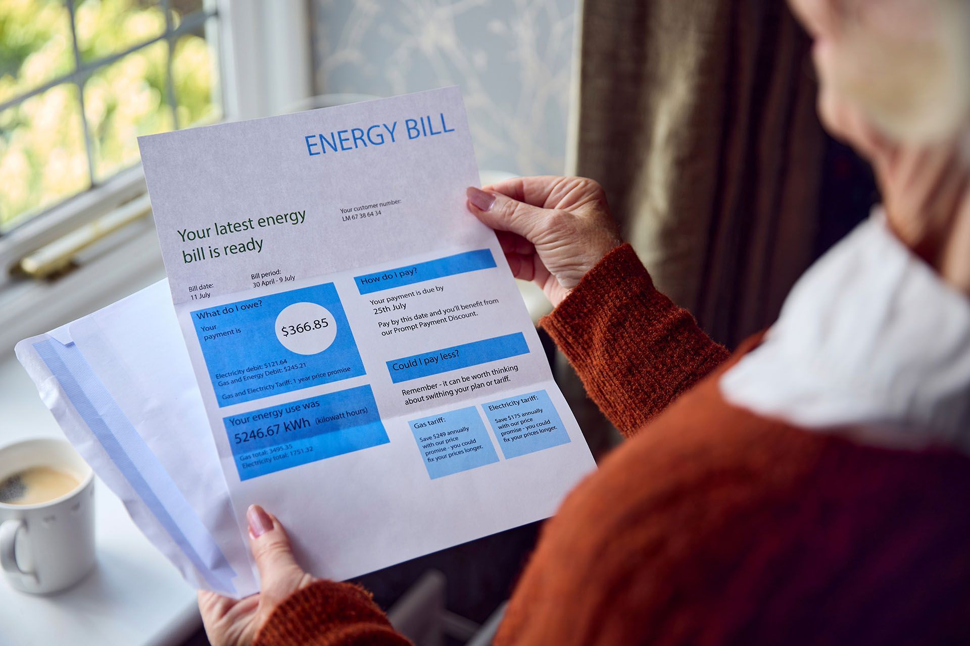 An elderly woman is holding an energy bill in her hands.