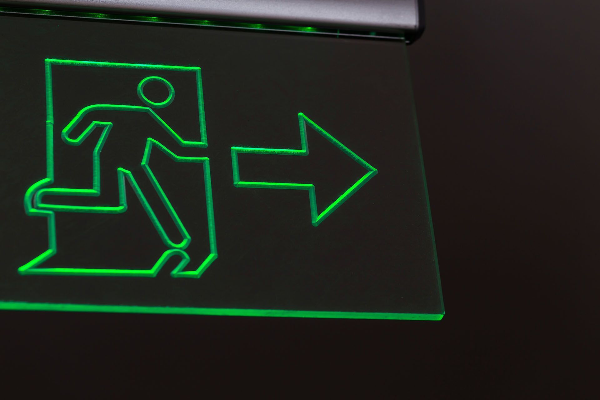 A green exit sign with a man running and an arrow pointing to the right.