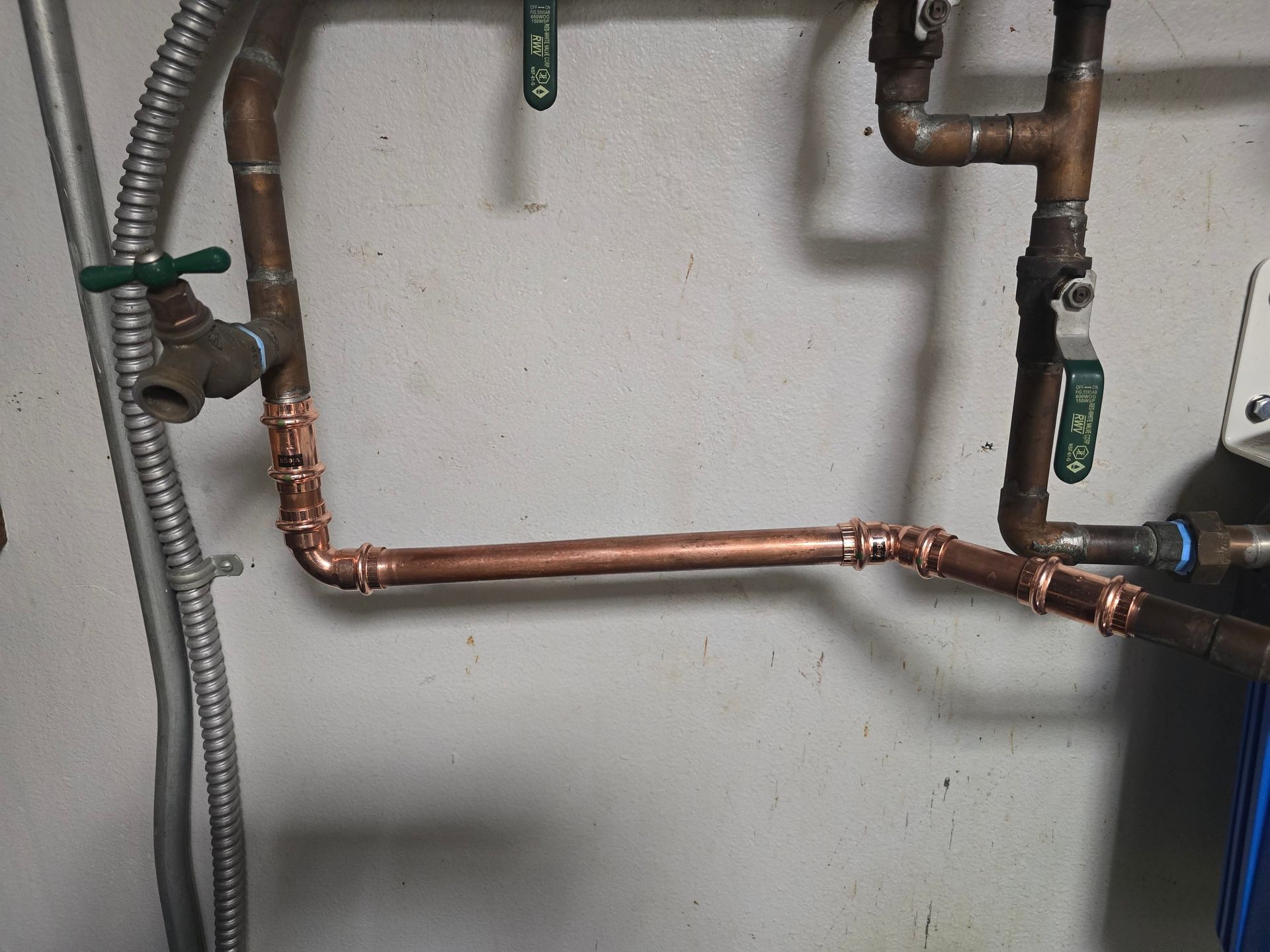 Copper pipes and valves mounted on a wall in a utility or plumbing area.