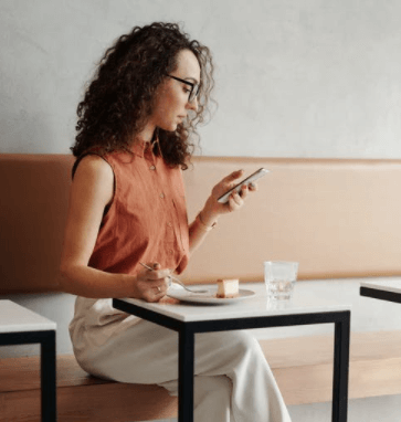 Woman in White Sleeveless Dress Sitting on Chair Browsing on Social Media