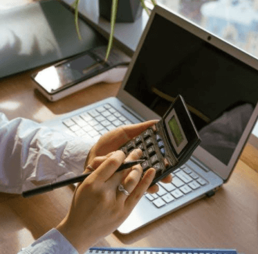 Person Using a Calculator and a Laptop