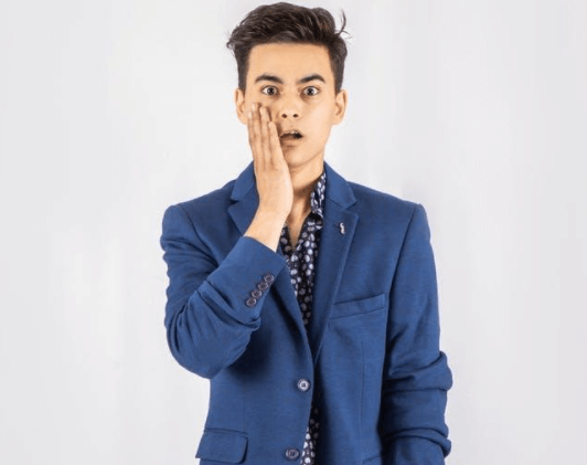 Shocked Man in Blue Blazer Standing In Front of White Background
