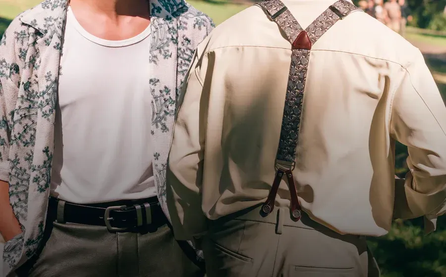 Two people in suspenders and patterned shirts standing side by side outdoors, cropped at the shoulders.