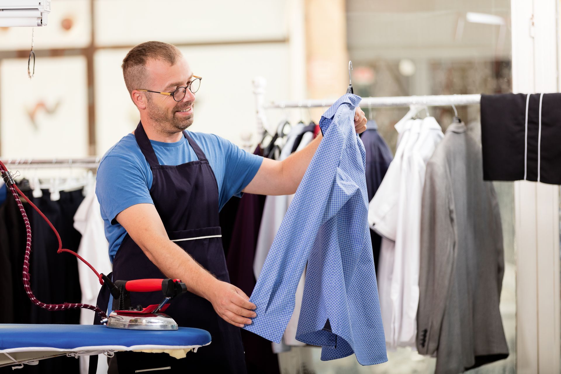 Man ironing a blue checkered shirt in a clothing shop