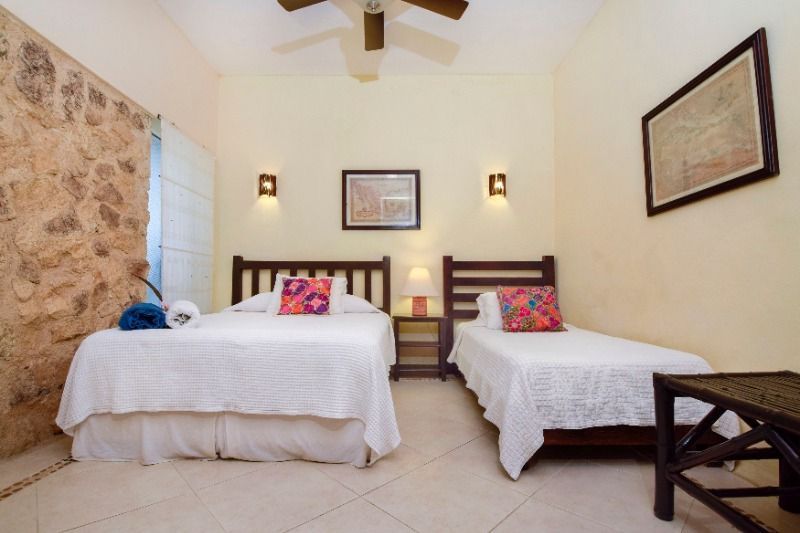 Small bedroom with two twin beds, white bedding, framed wall art, and a ceiling fan