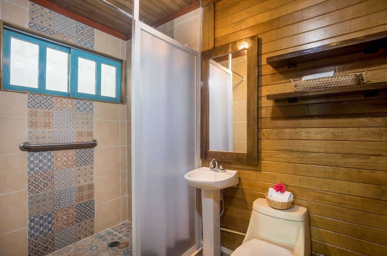 Small bathroom with tiled shower, frosted curtain, sink, toilet, and wood-paneled walls.