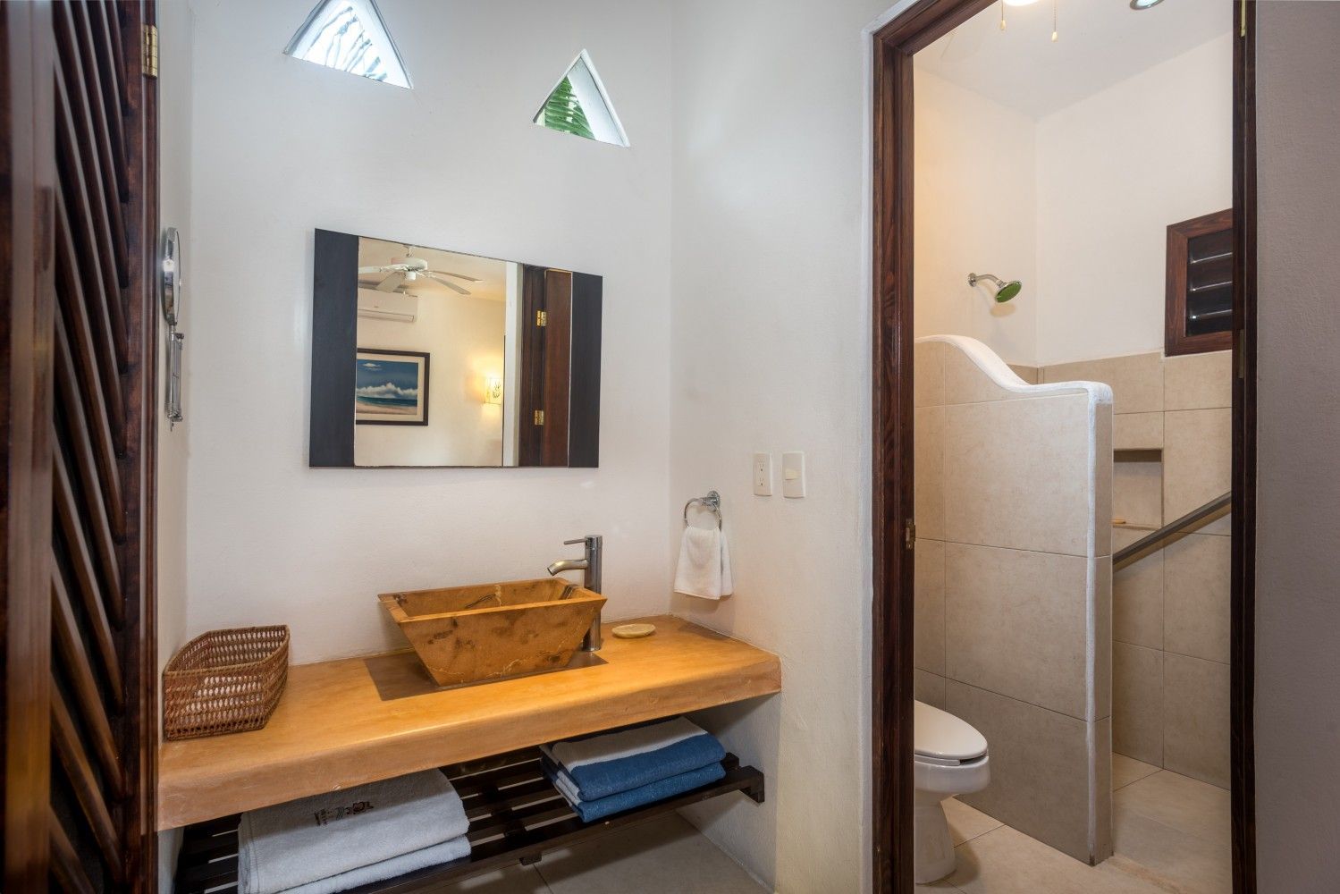 Modern bathroom vanity with wooden bench, mirror, and adjacent shower area