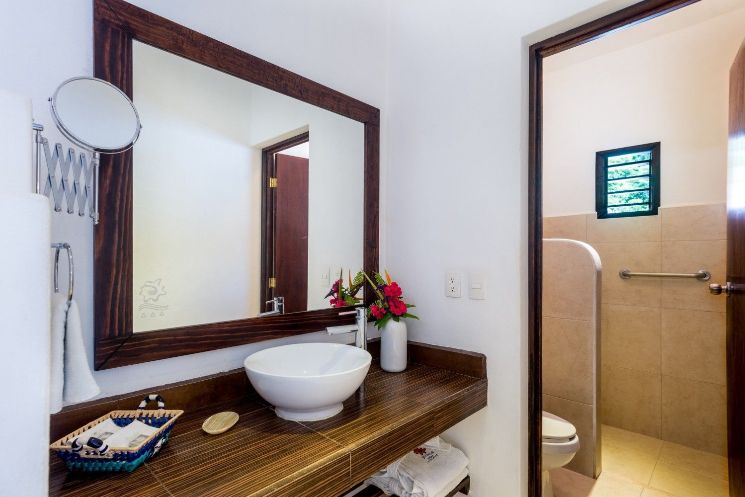 Bathroom vanity with round white sink, large mirror, wood countertop, and open door to toilet area.