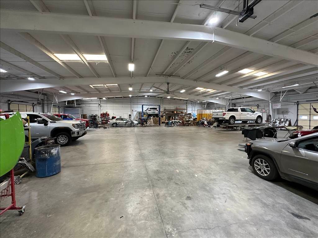 Wide shot of a large auto repair shop, multiple cars on lifts and waiting for service.
