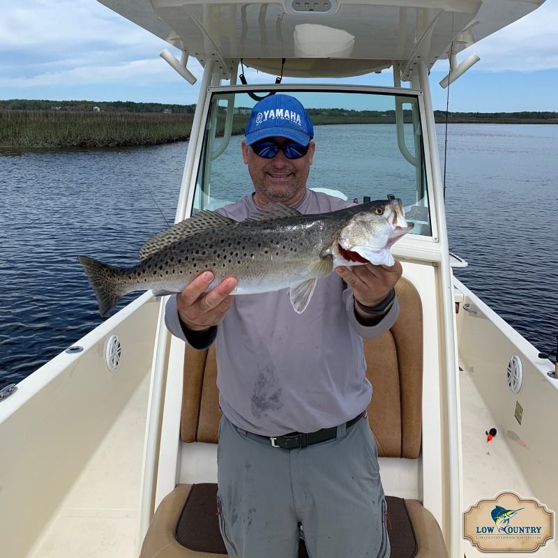 Person on a boat holding a large striped bass with open water behind him
