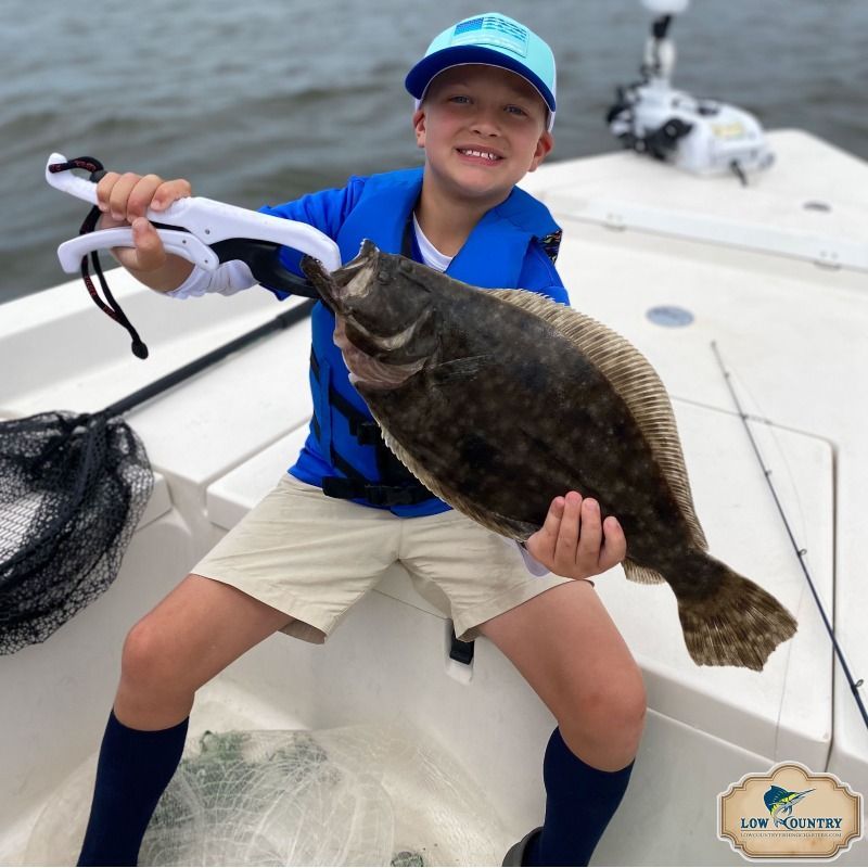 Person in blue shirt and cap holding a large fish on a boat deck.