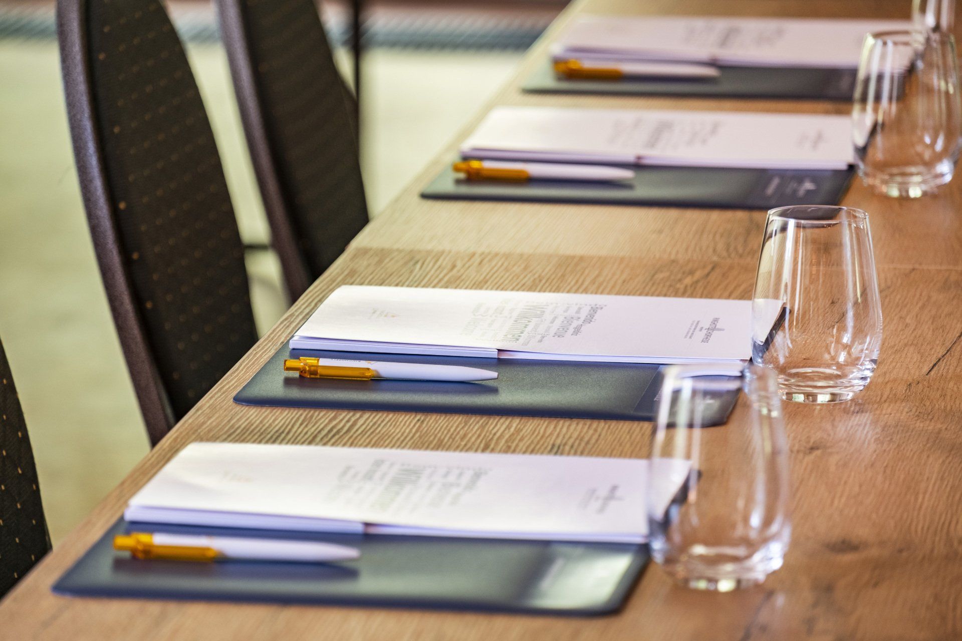 Konferenztisch mit Papieren, Stiften und Wassergläsern, bereit für ein Meeting.