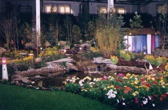 Flower bed with stone retaining wall, rocks, and vibrant yellow and orange flowers.