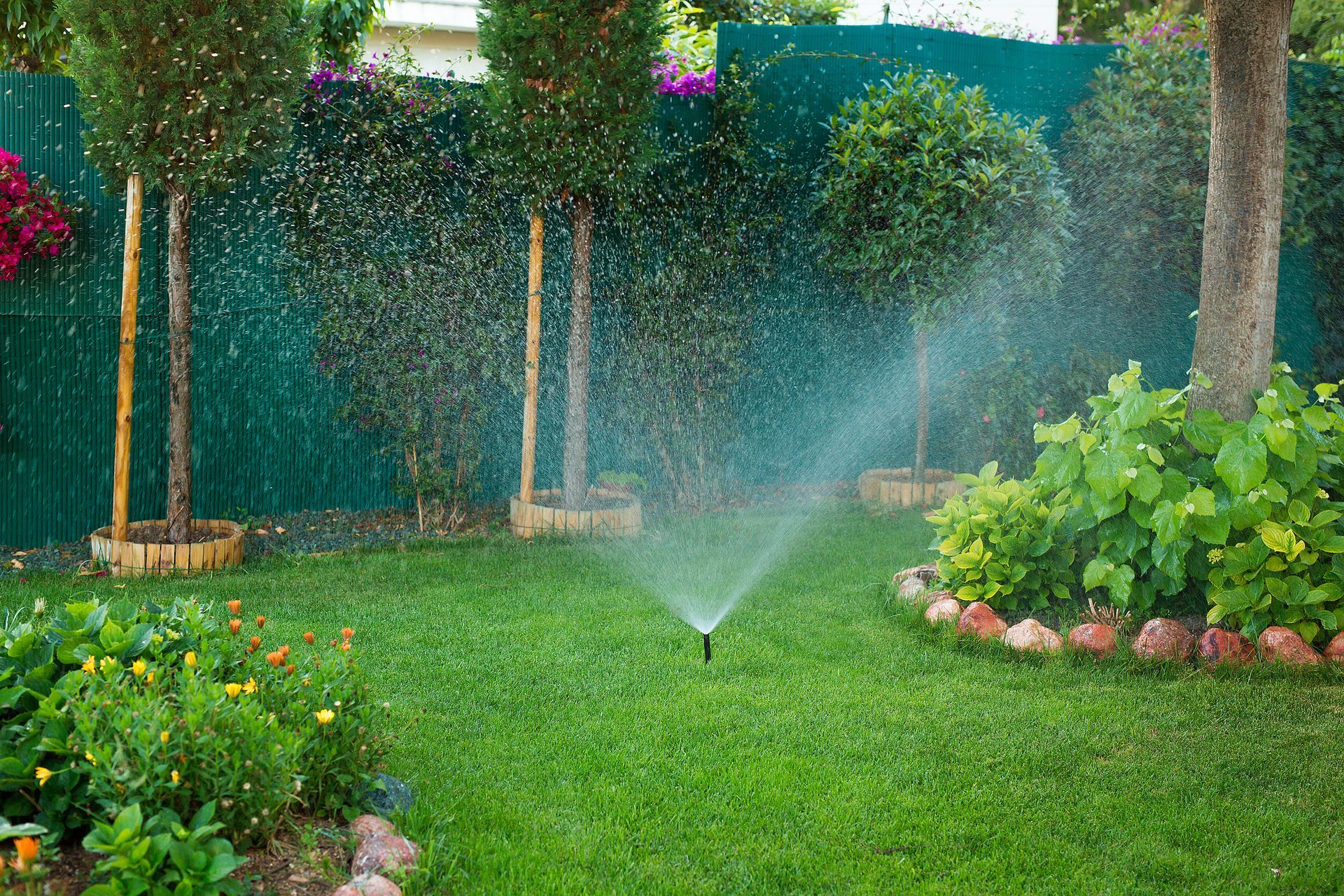 Flower bed with stone retaining wall, rocks, and vibrant yellow and orange flowers.