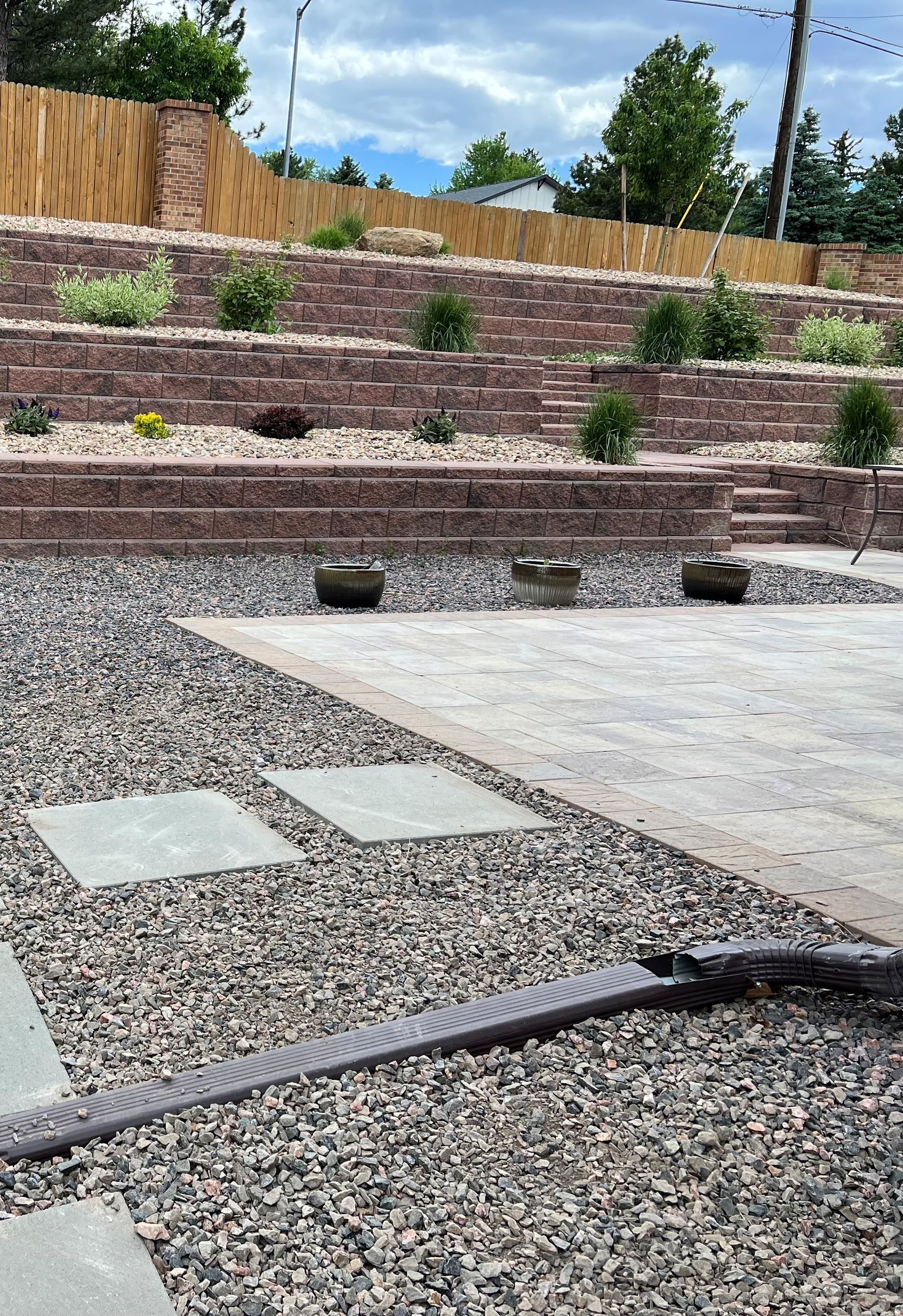 Multi-tiered red brick retaining wall with gravel and stone pathway.