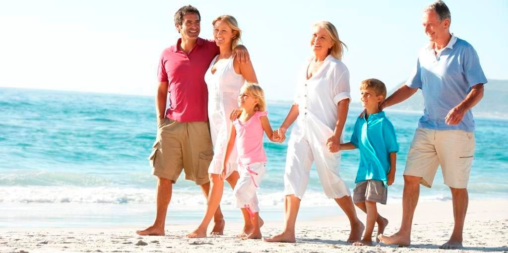 Family walking hand in hand on a sunny beach near the ocean
