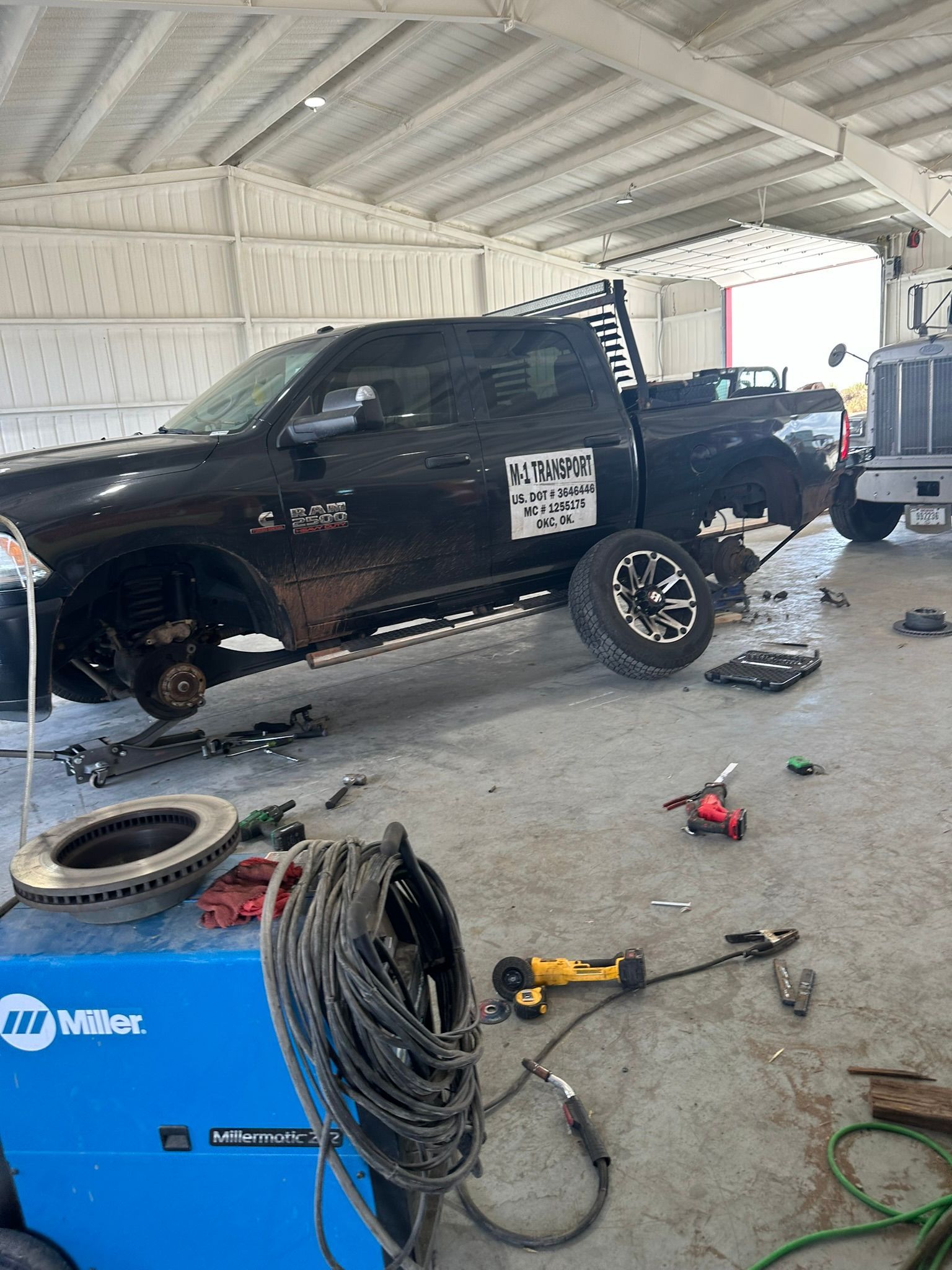 A black truck is being worked on in a garage.