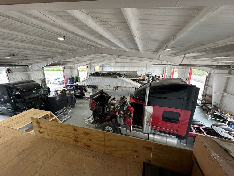 A man is working on a truck engine in a garage.
