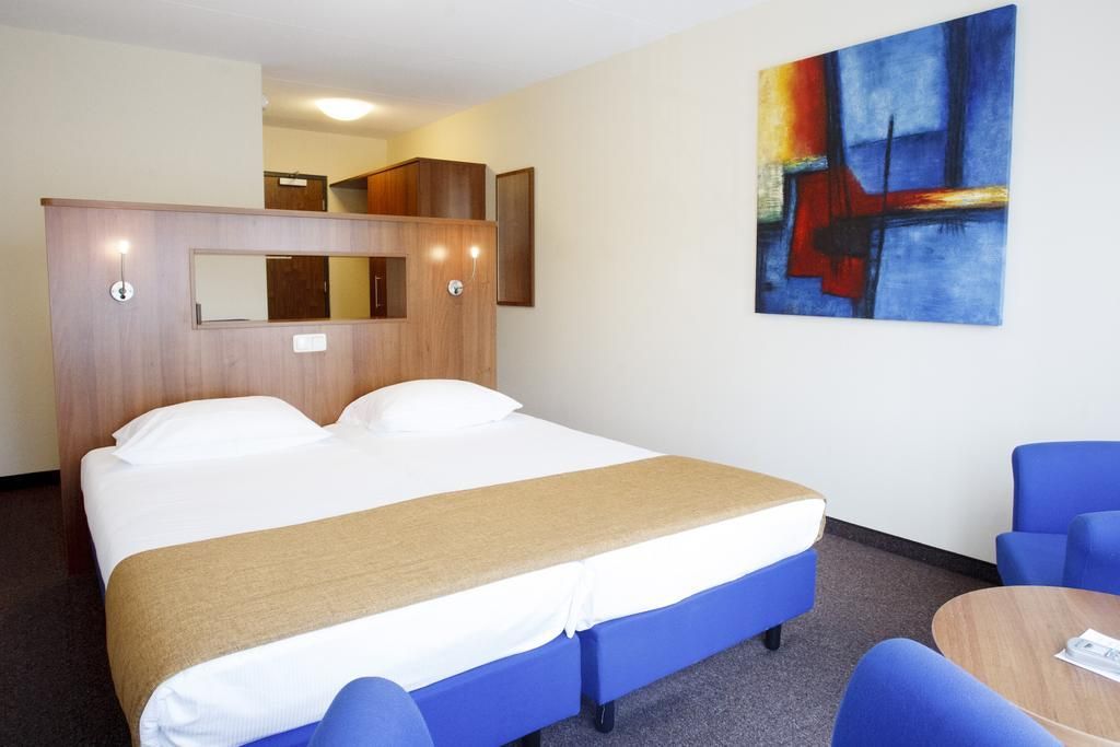 een hotelkamer met twee bedden en een schilderij aan de muur
