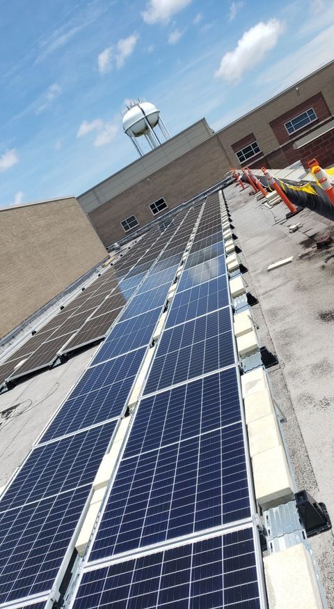 A man is installing solar panels on the roof of a building.
