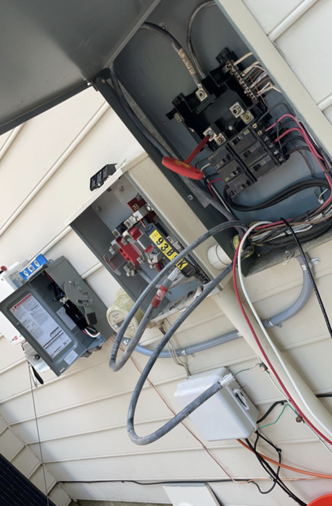 A man is using a multimeter to test an electrical box.