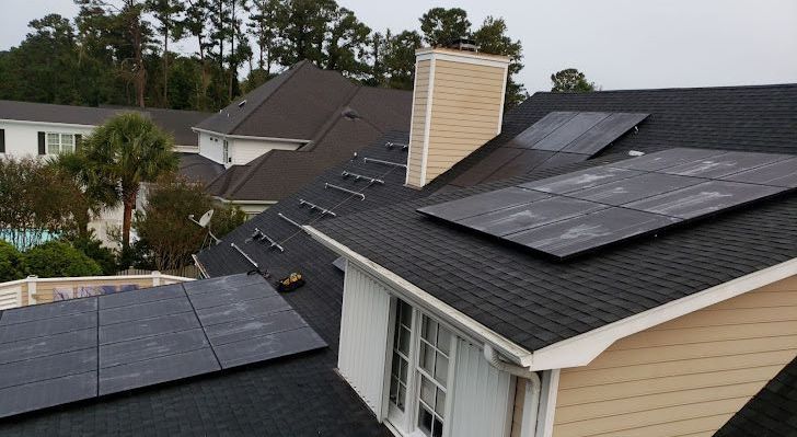 A house with solar panels on the roof and a chimney.
