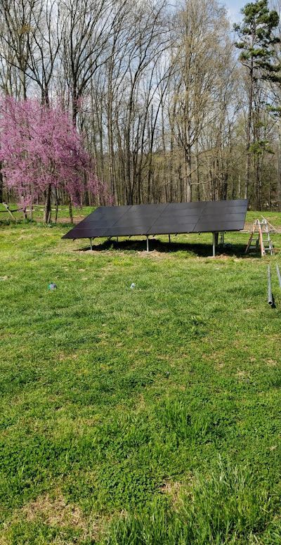 A solar panel is sitting in the middle of a grassy field.