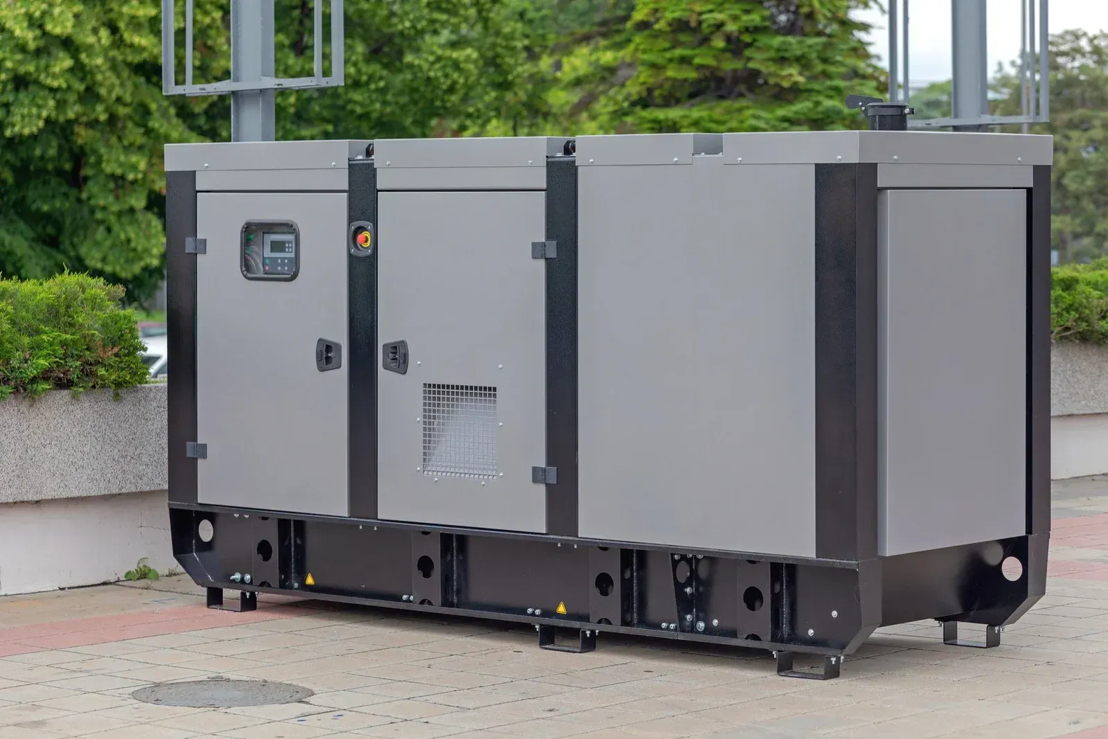 A large gray and black generator is parked on a sidewalk.