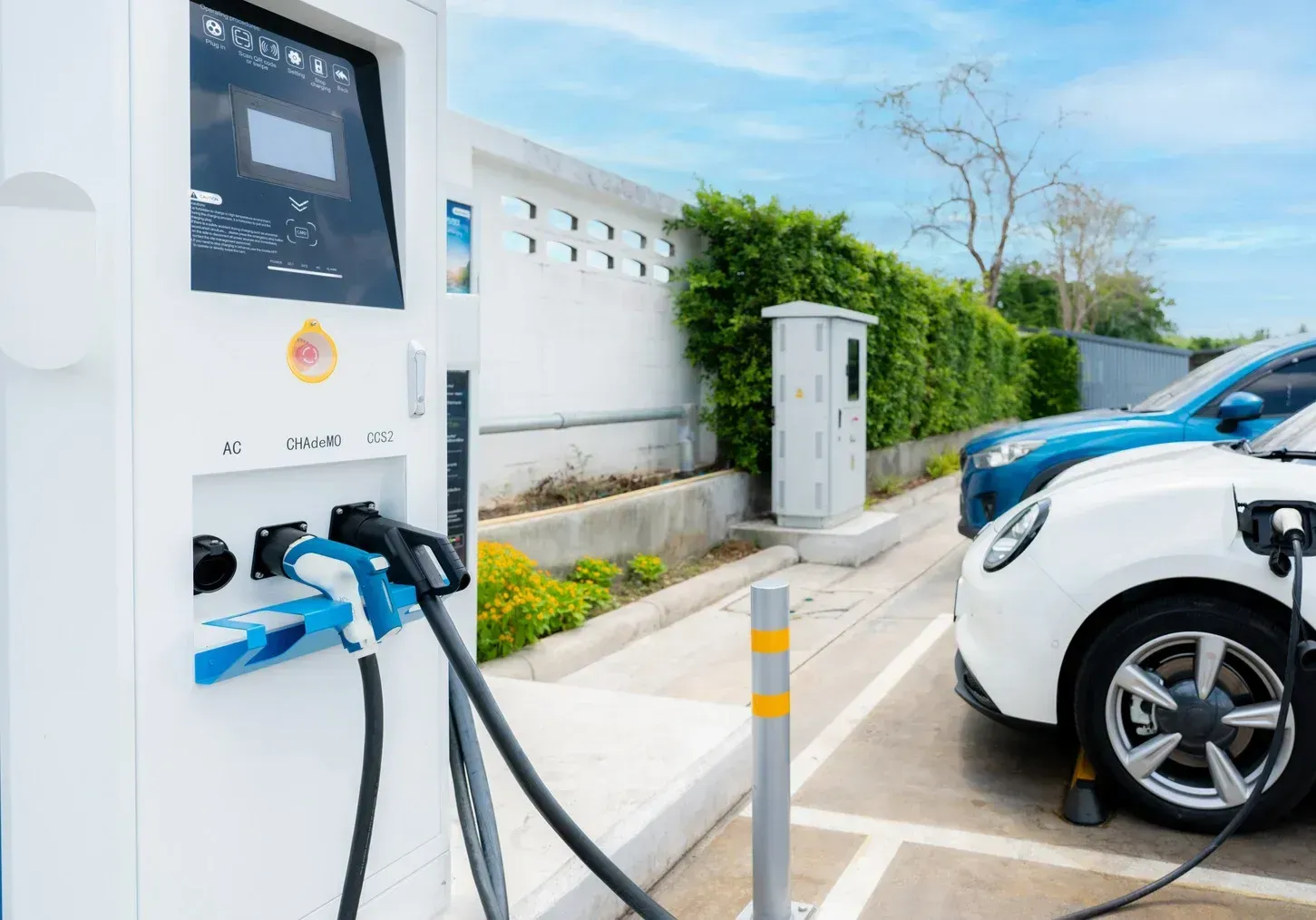Two electric cars are being charged at a charging station.
