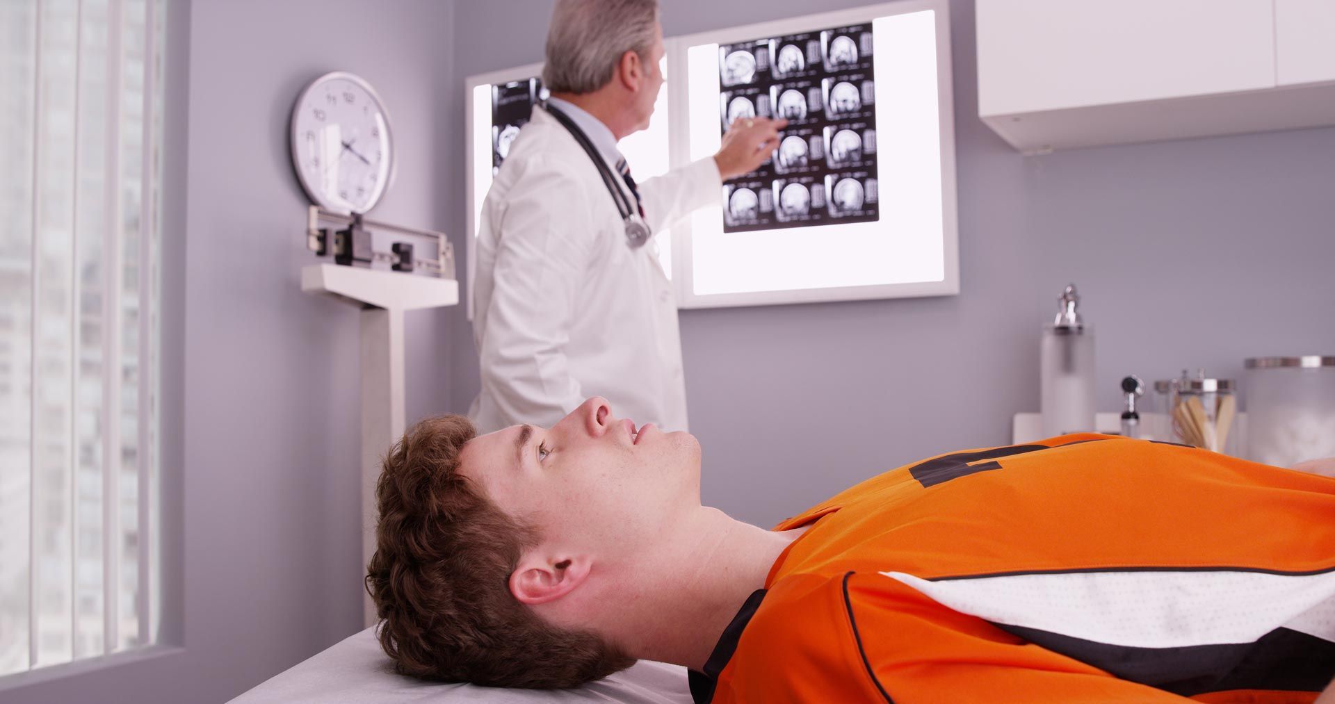 Doctor reviewing X-ray with patient lying on exam table in clinic