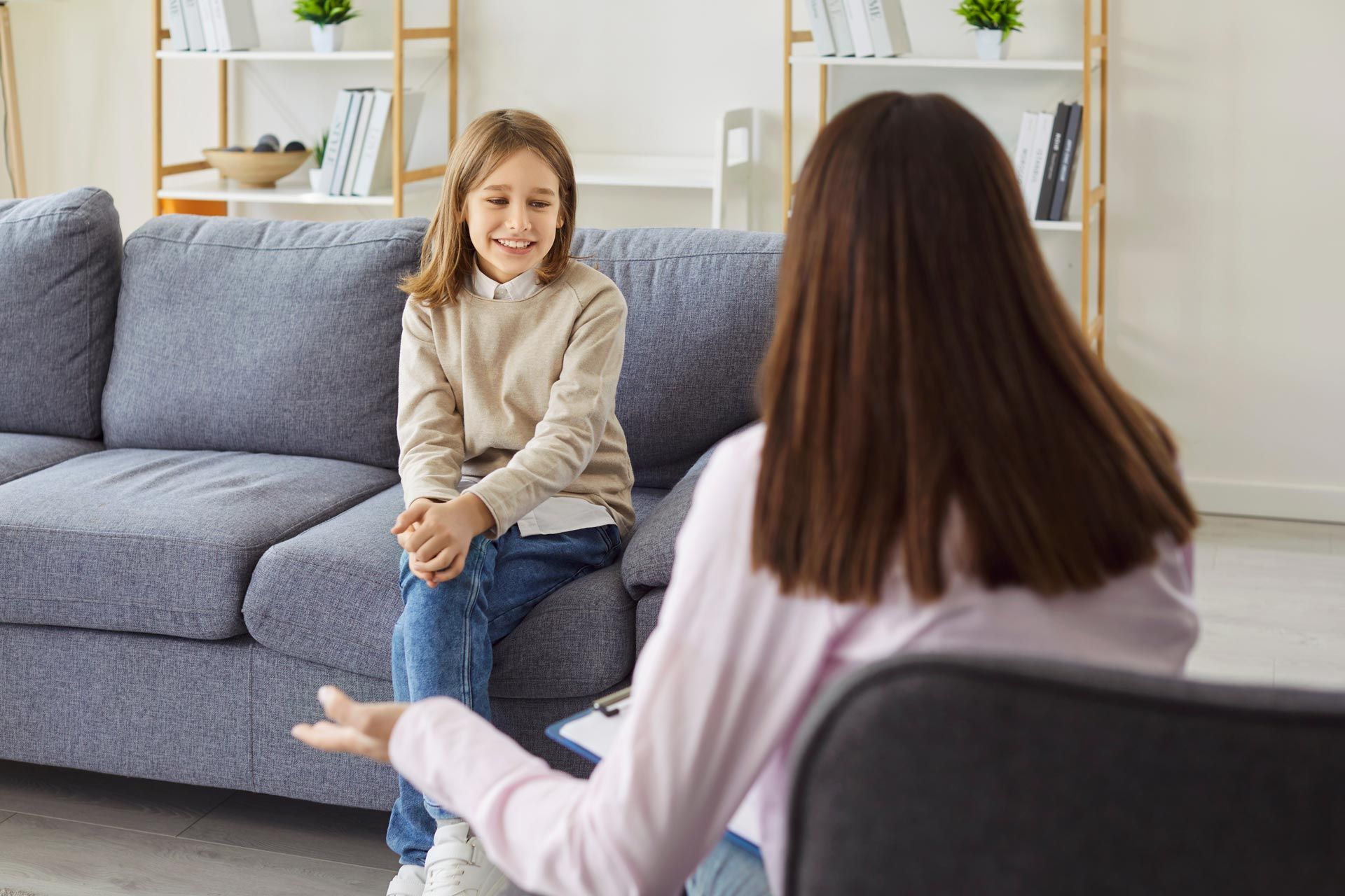 Counselor talking with a smiling client on a gray sofa in a bright living room