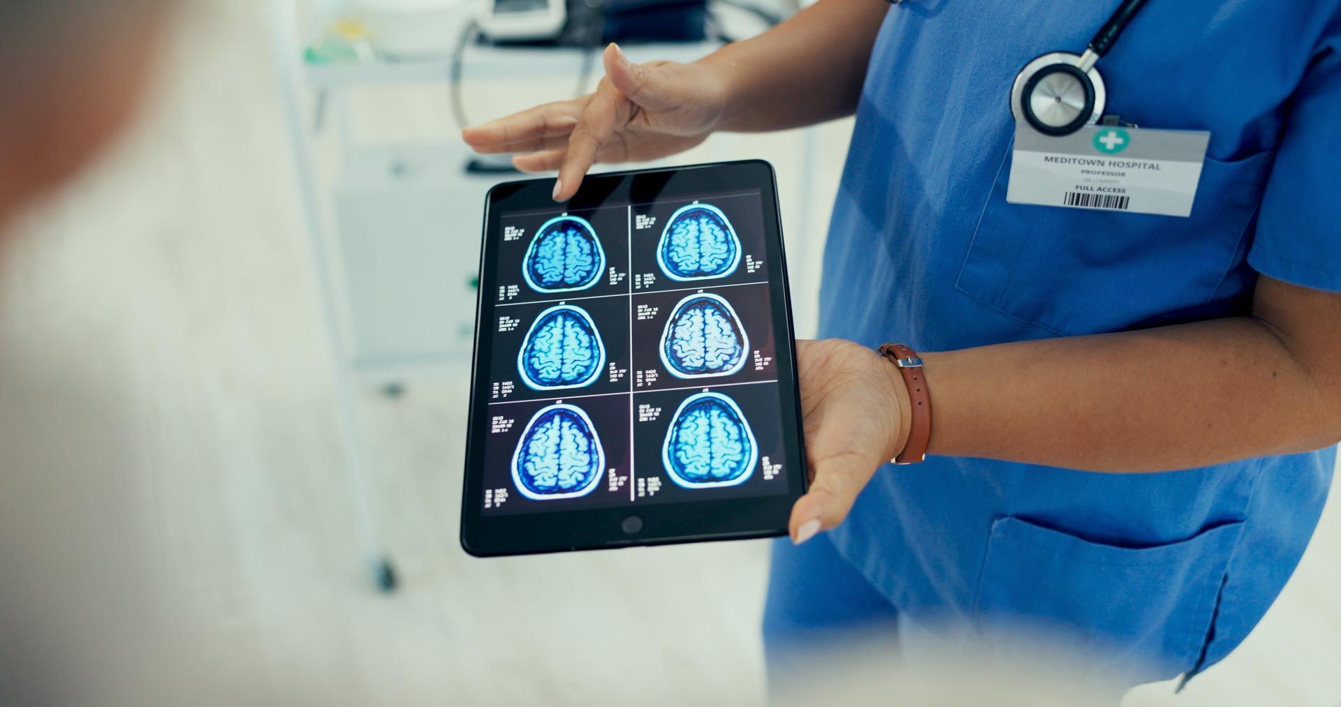 Healthcare worker holding a tablet displaying brain scan images in a hospital setting