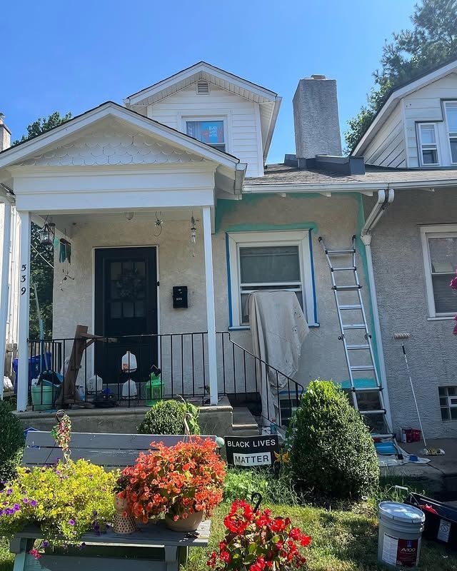 A house is being painted with a ladder in front of it.