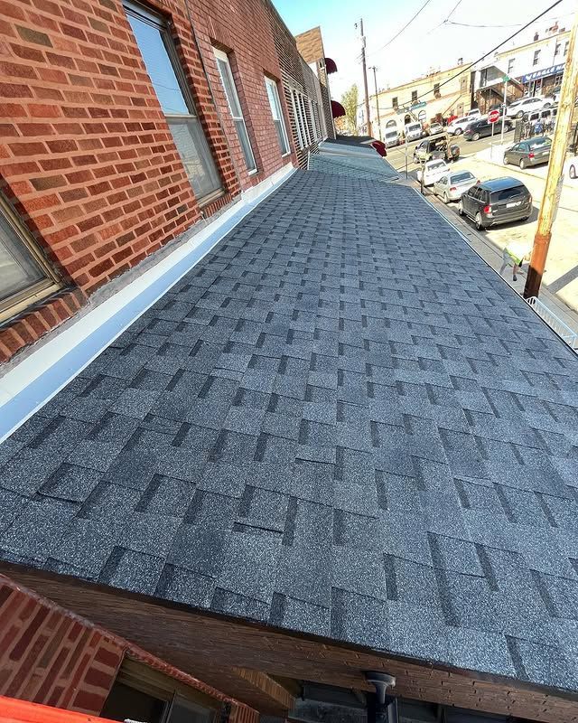The roof of a brick building with a black shingle roof.