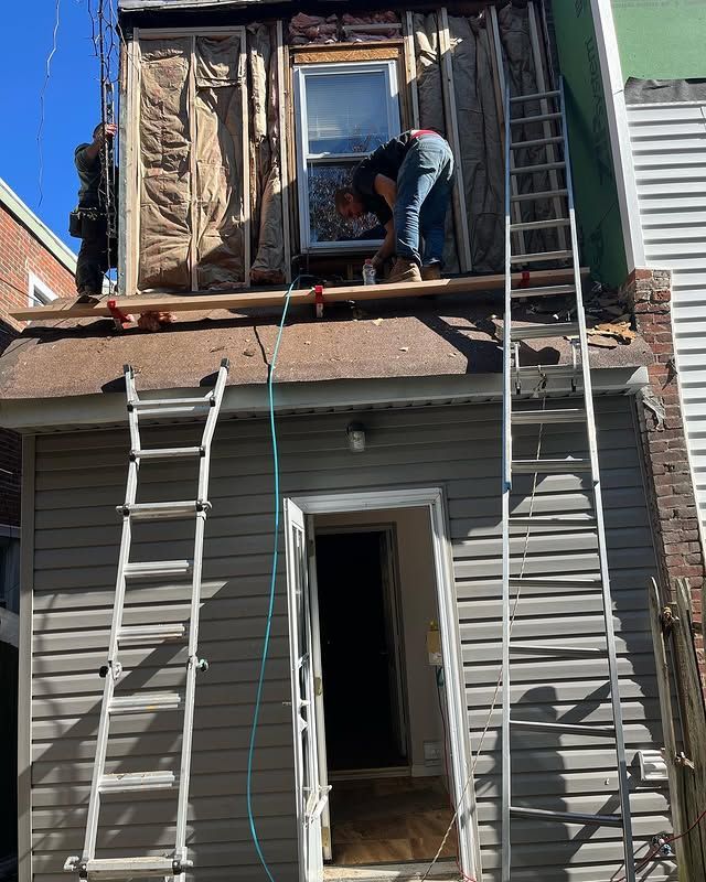 A man is working on the roof of a house with a ladder.