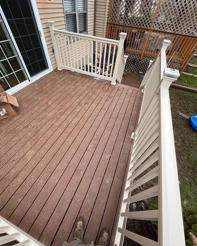 A person is standing on a wooden deck with a white railing.