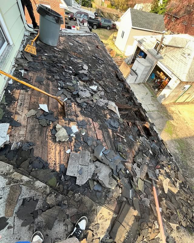A person is standing on the roof of a house with a broom.