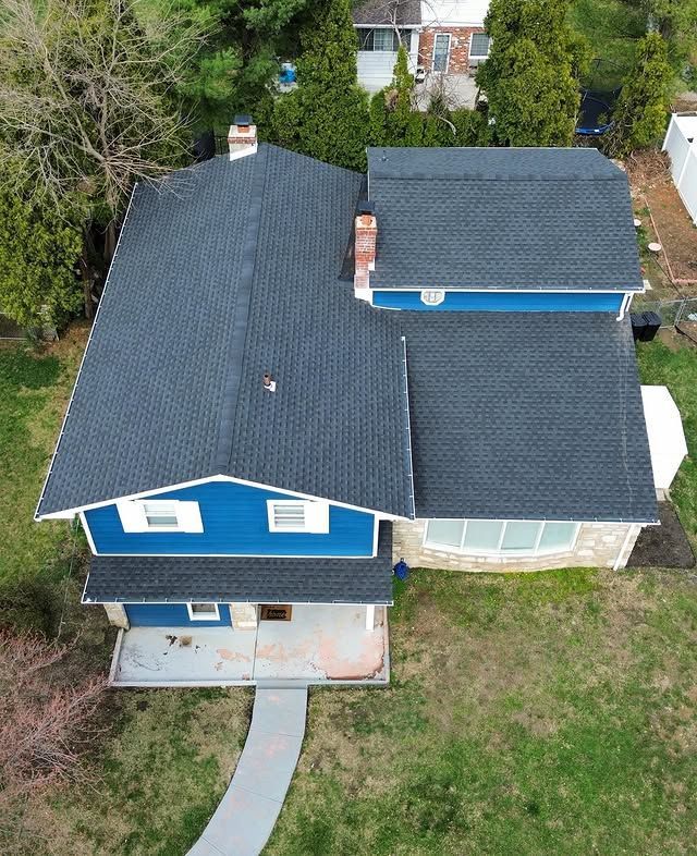 An aerial view of a blue house with a black roof
