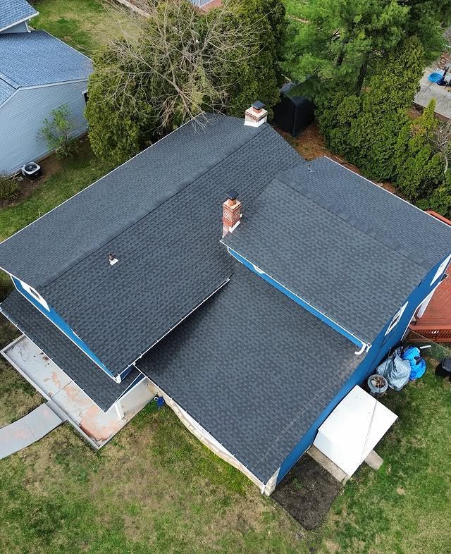 An aerial view of a house with a black roof and a chimney.