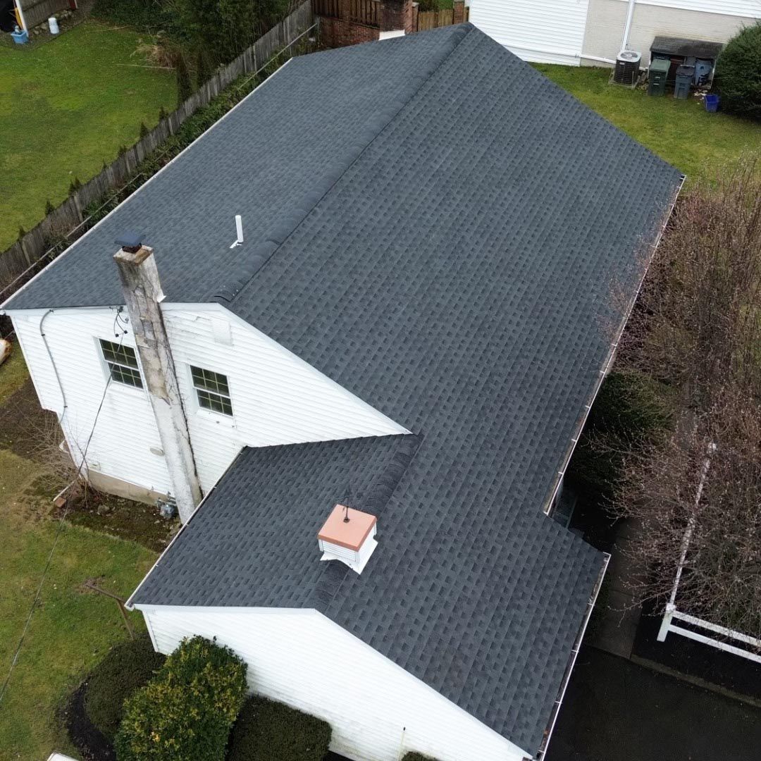 An aerial view of a white house with a black roof.
