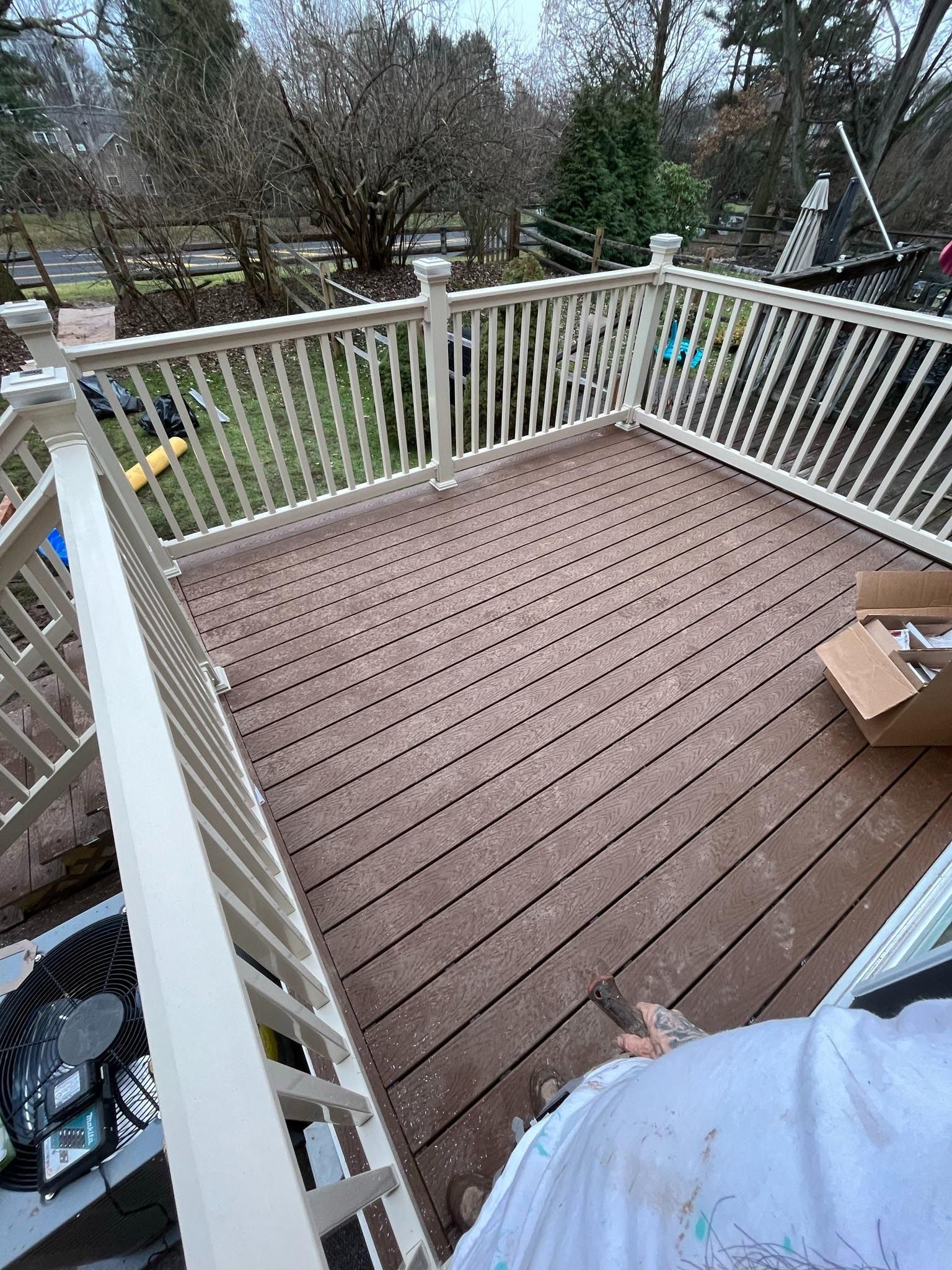 A wooden deck with a white railing and a box on it.