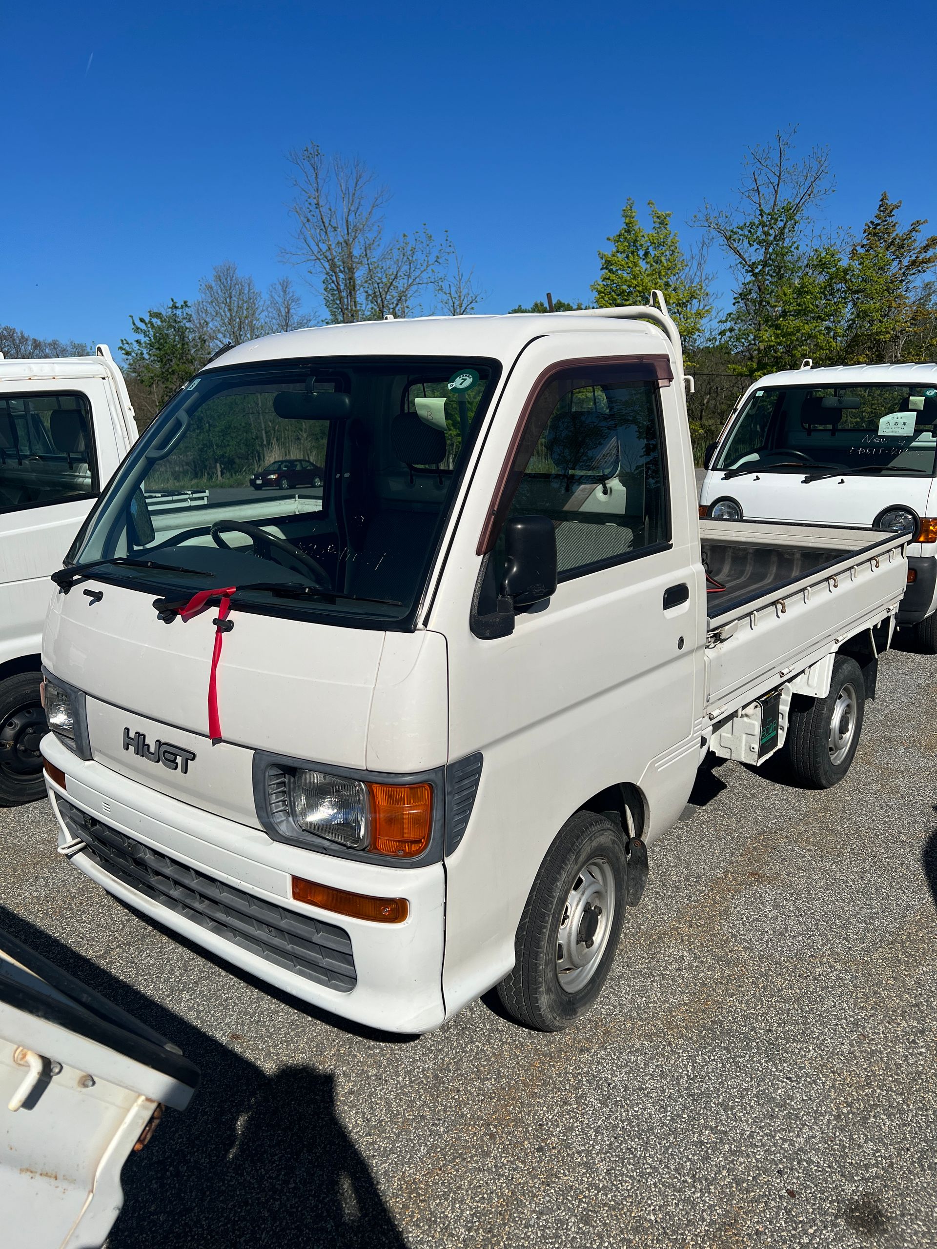 White Daihatsu Hijet mini truck on a rural road