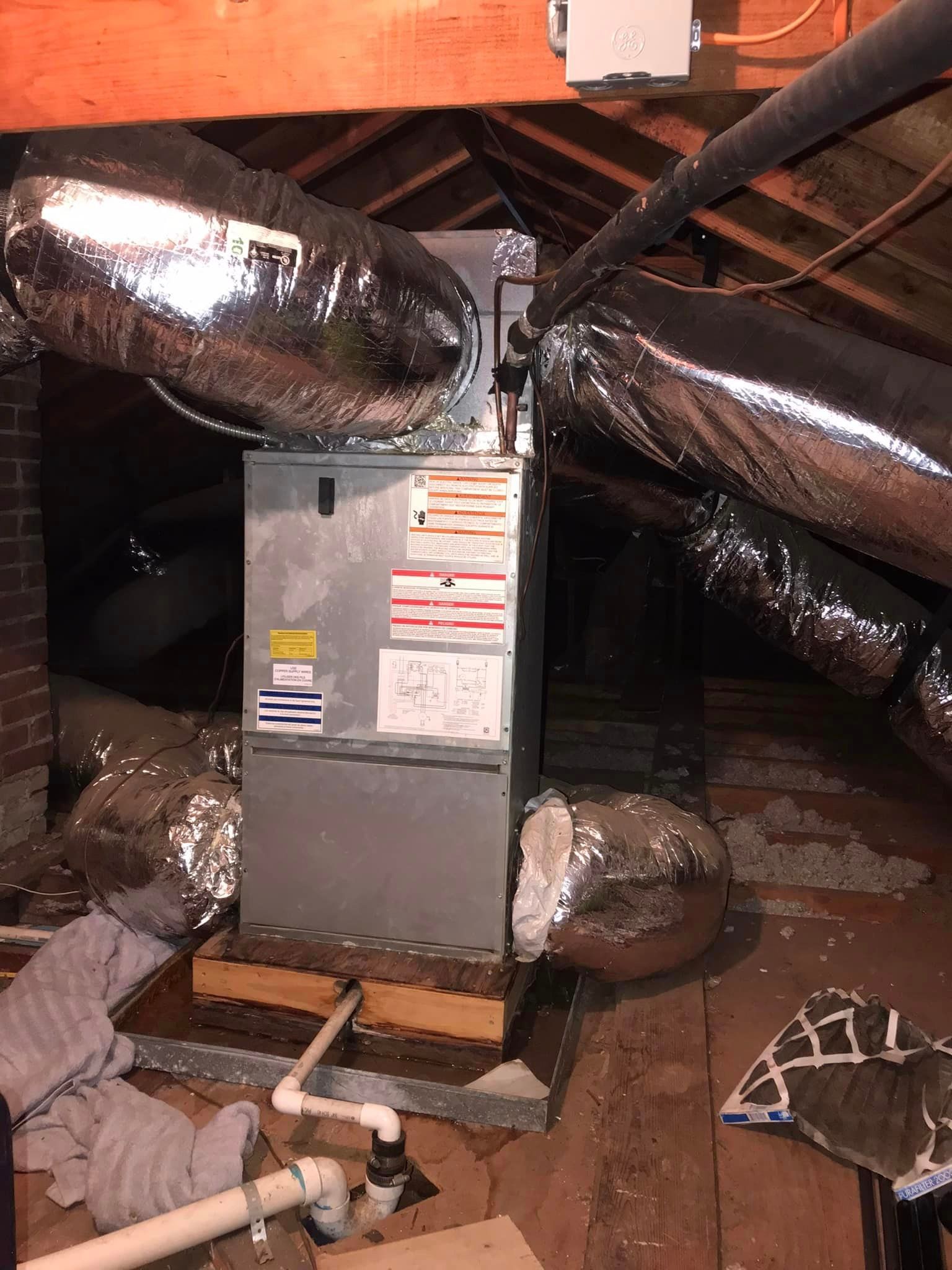 An air conditioner is sitting in the attic of a house.