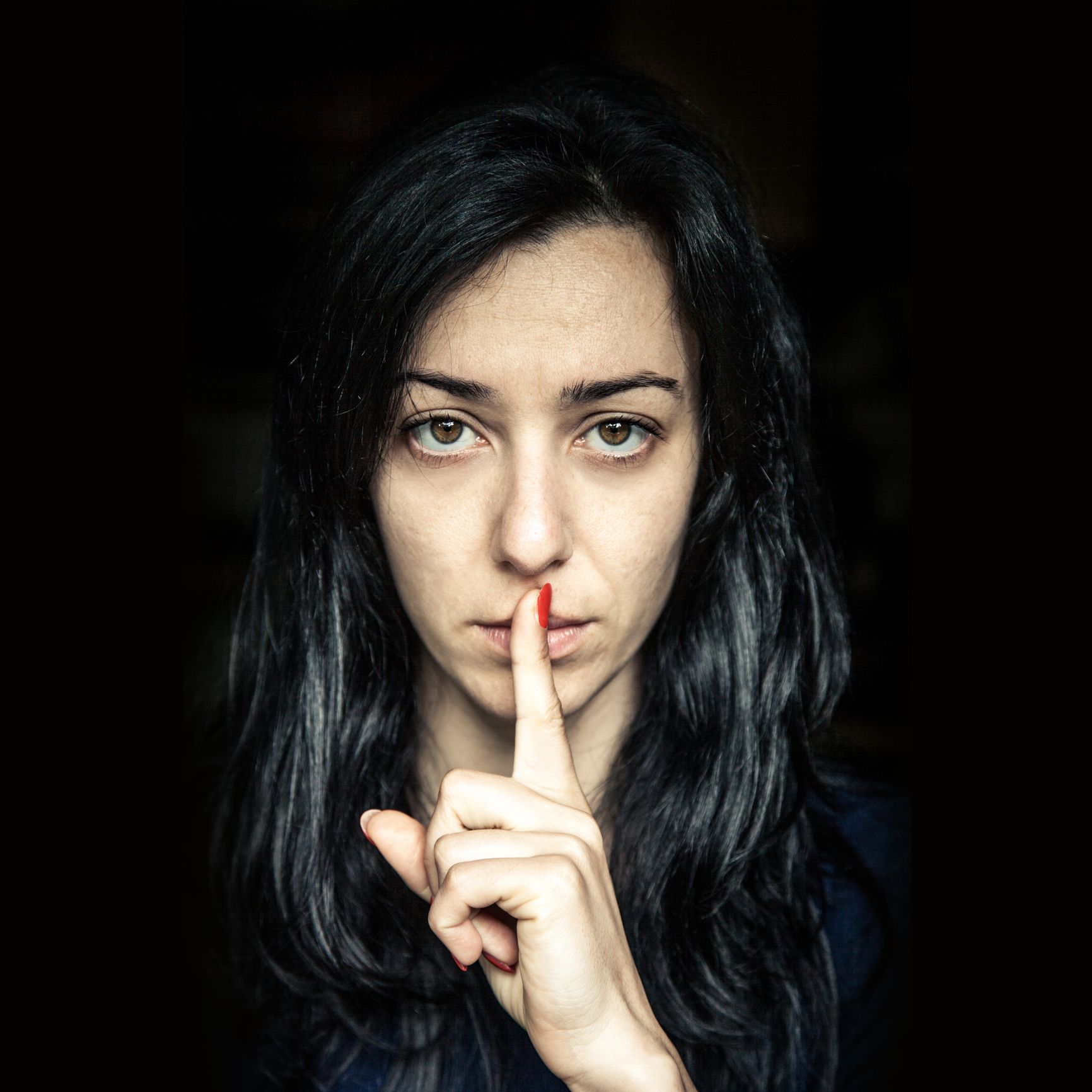 A woman is holding her finger to her mouth.