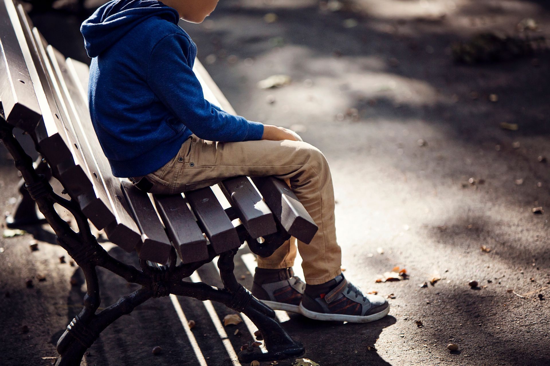 A young boy is sitting on a park bench.