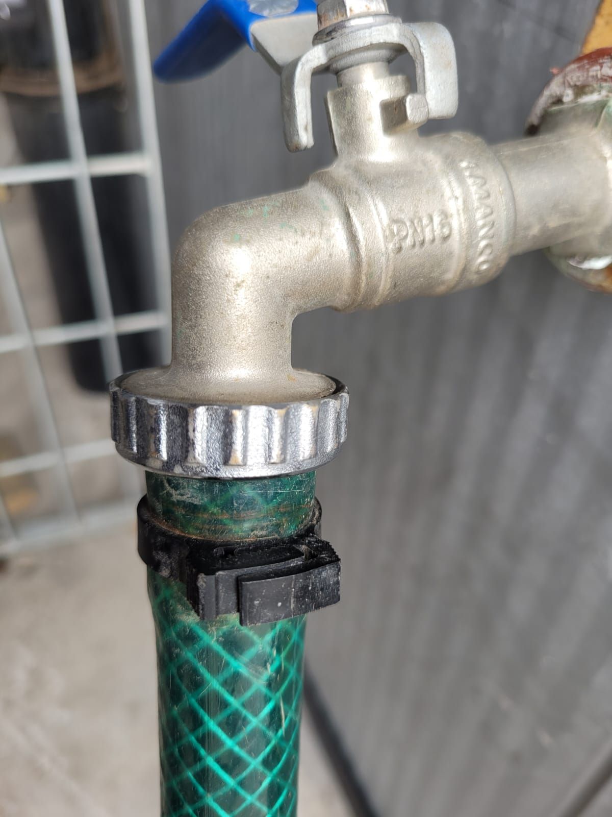 Un grifo de agua con una manguera verde adjunta, de cerca.