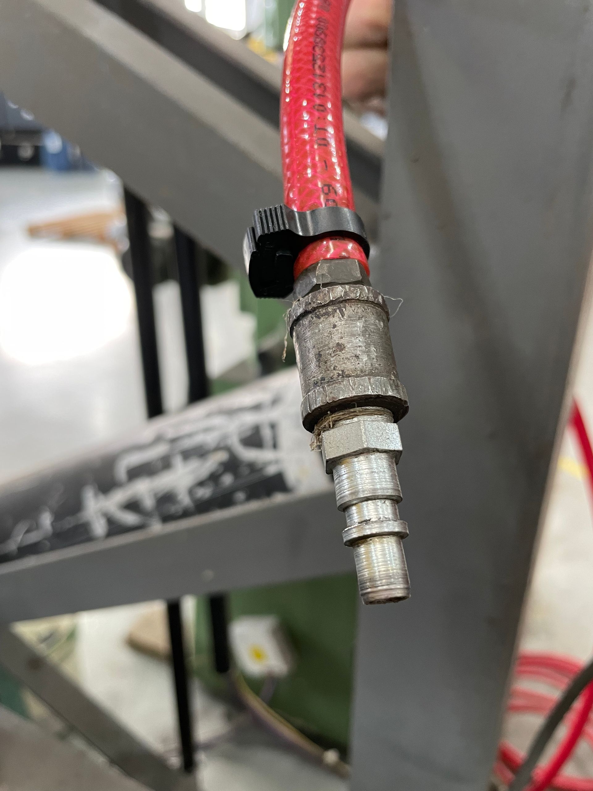 Primer plano de un conector de manguera de aire; manguera roja, clip negro, accesorio de metal 