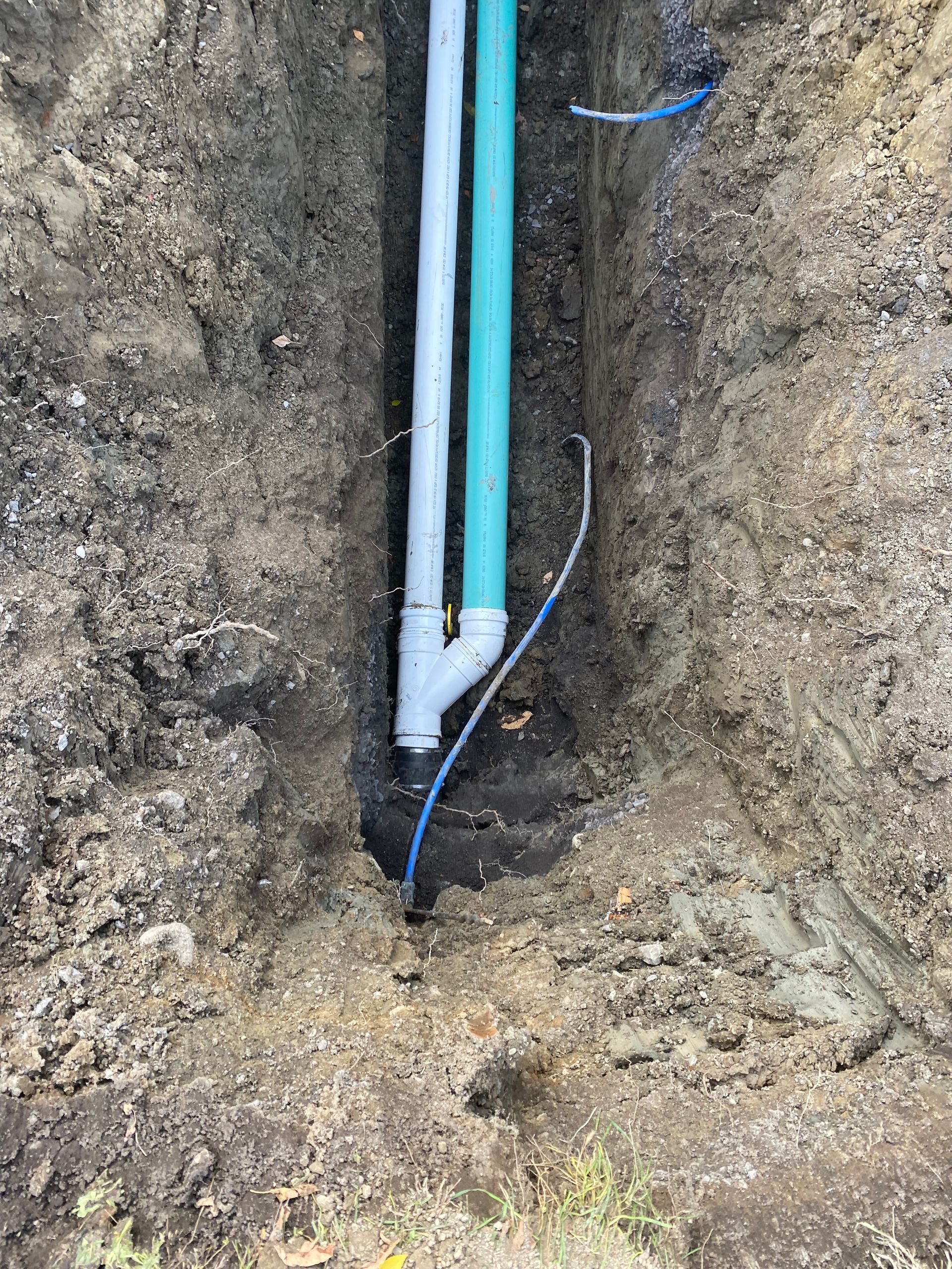A drain pipe is being installed in a hole in the ground.