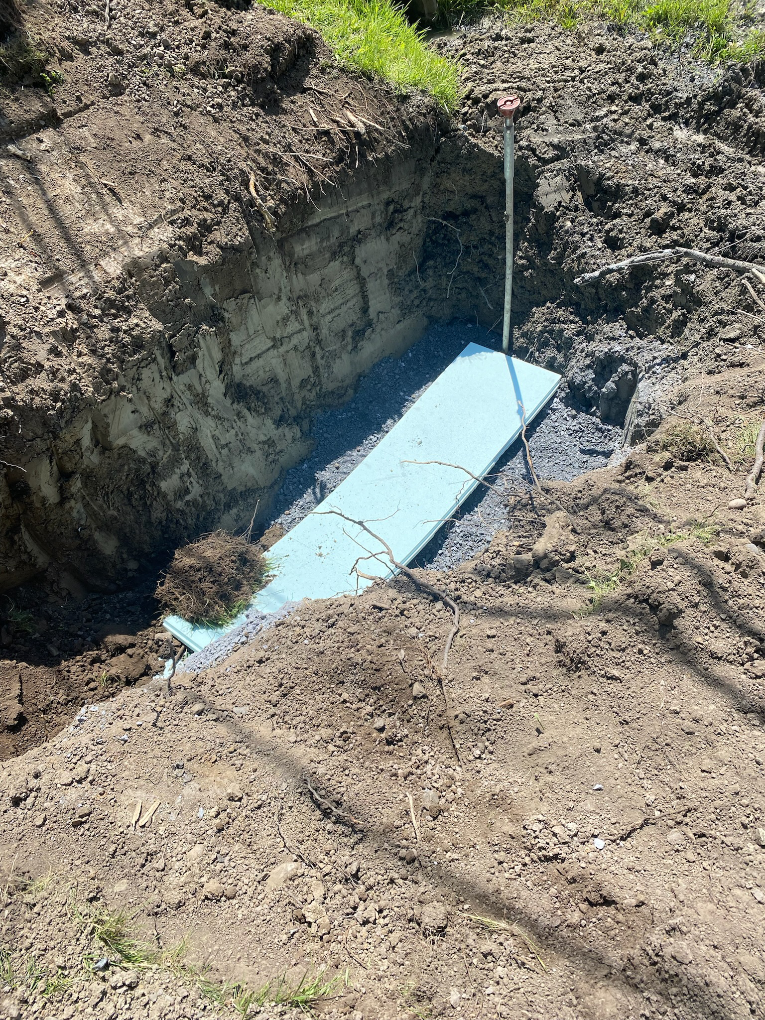A blue pipe is sitting in the dirt next to a shovel.