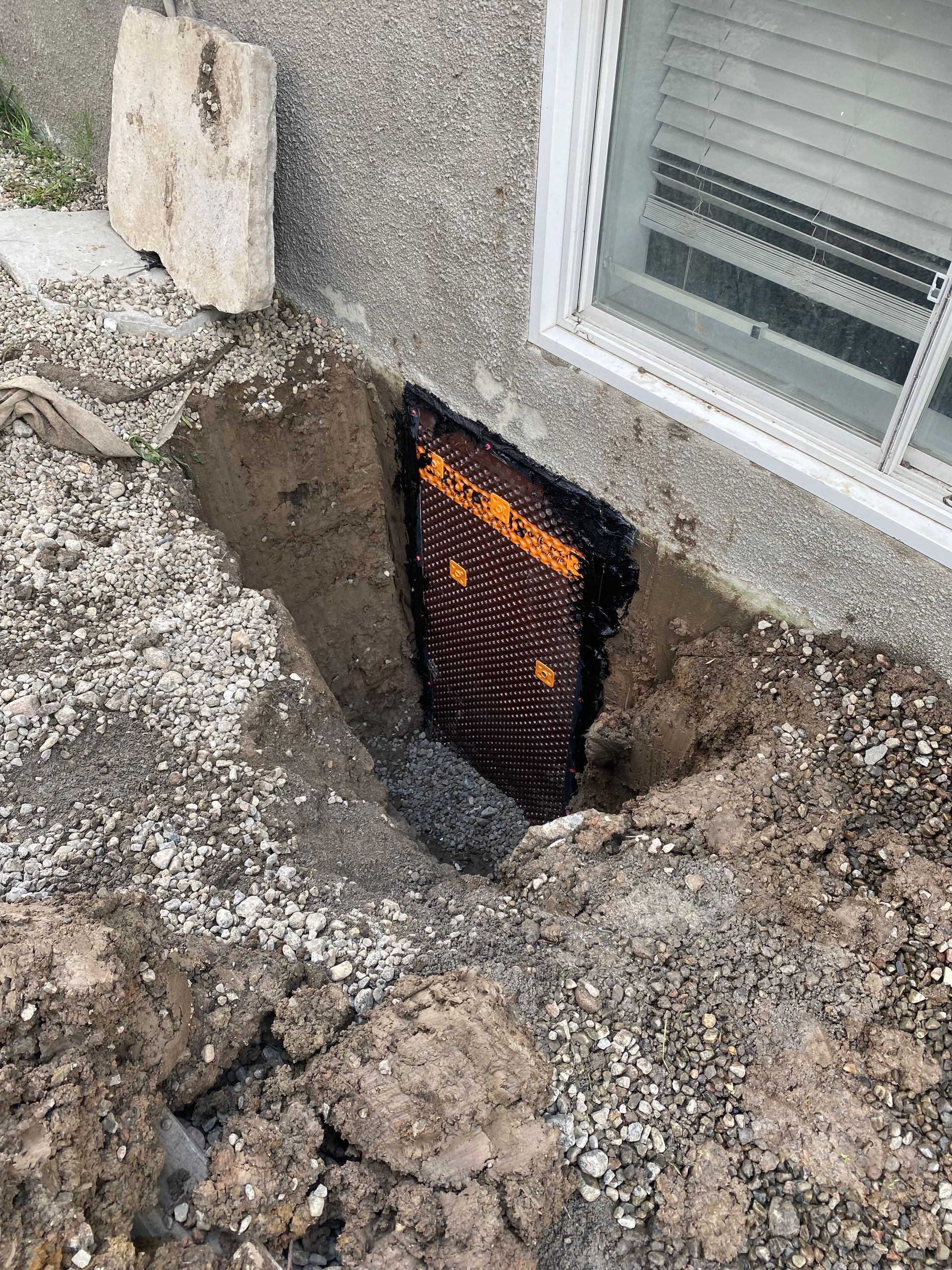 There is a hole in the ground next to a window.